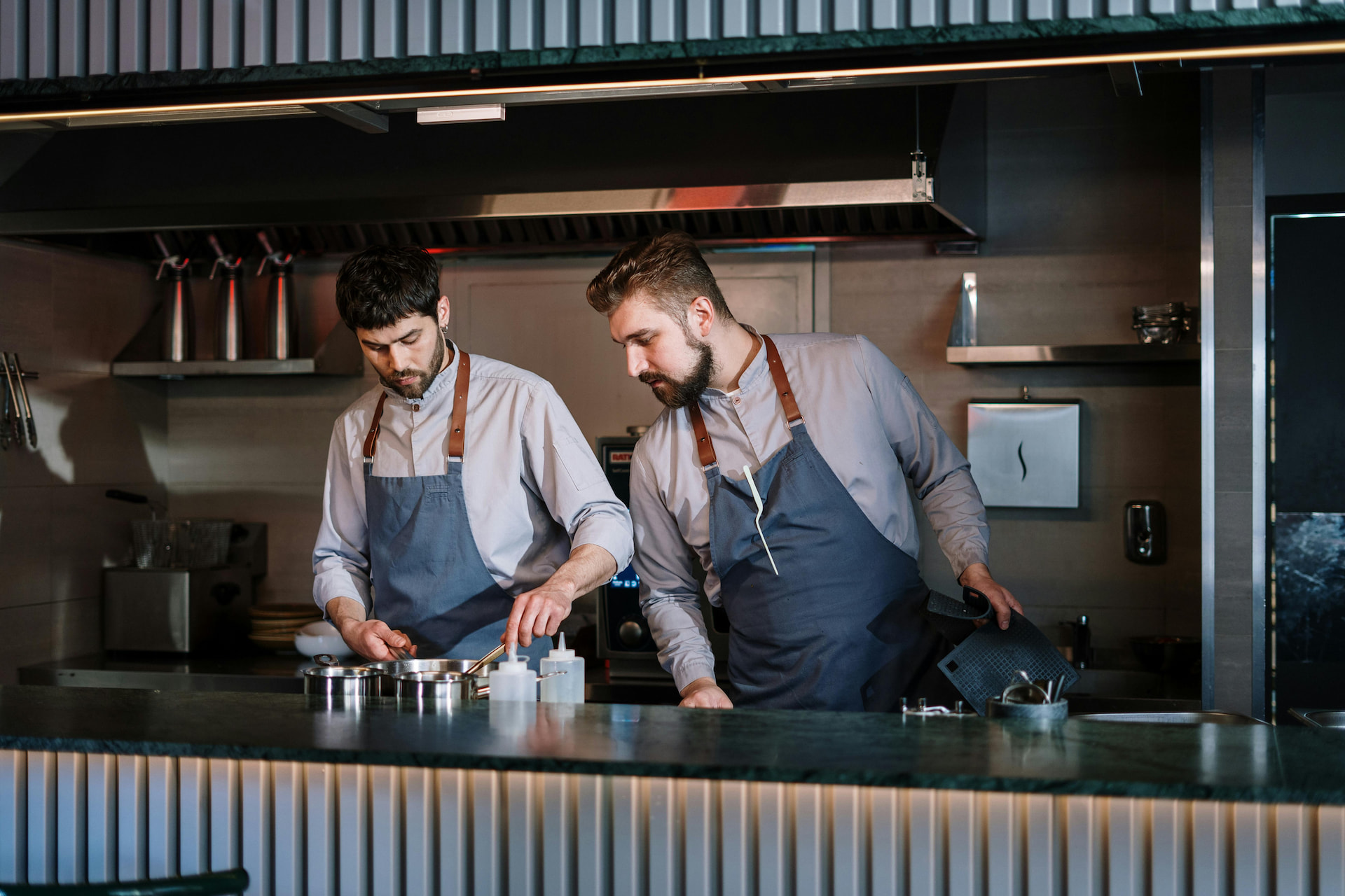 A sous chef overlooking a chef working in the kitchen.